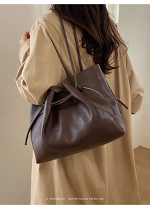 Detail of dark brown faux leather tote bag showing smooth texture and drawstring design
