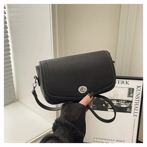 Close-up of black lychee grain leather crossbody bag with silver metal swivel lock