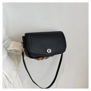 Détail d'un sac en cuir noir avec fermoir rotatif argenté et bandoulière amovible