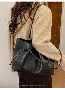 Detail of black glossy leather tote bag showing fine drawstring knot and wrinkled texture