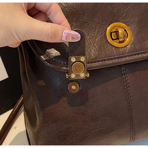 Macro detail of dark brown leather backpack with golden magnetic clasp closure