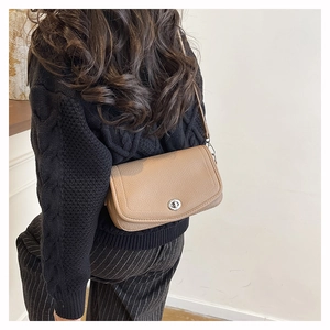 Détail du sac bandoulière en cuir camel avec texture litchi et fermoir tournant argenté