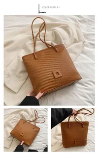 Detailed view of brown tote bag with vertical pleats and square leather accent
