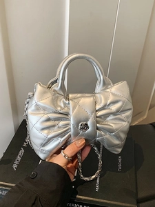 Sac à main argenté matelassé en forme de nœud avec fleur noire et bandoulière chaîne