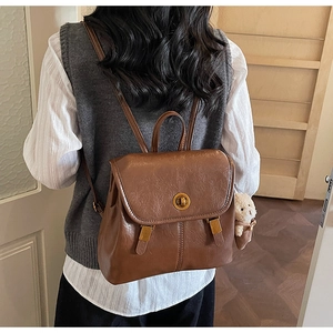 Rear view of model wearing a vintage brown faux leather backpack with plush bear charm