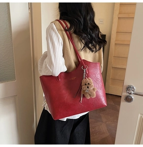 Detail of red shiny leather tote bag with white text and cute bear charm pendant