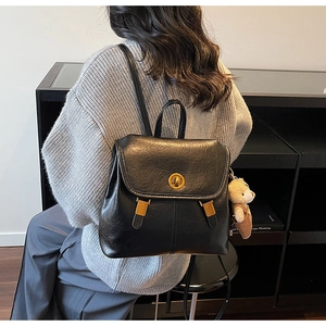 Detailed view of black leather vintage backpack with gold twist lock and bear charm