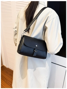 Rear view of model wearing a black square shoulder bag with a silver metal buckle