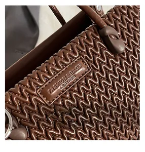 Detail of dark brown leather handbag featuring unique wavy embossed texture and brand logo