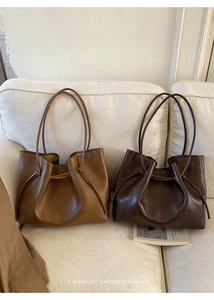Detail of brown and dark coffee tote bags with knotted handles on a beige fabric sofa