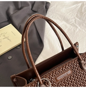 Close-up of dark brown bucket bag featuring wave quilting and silver logo plaque