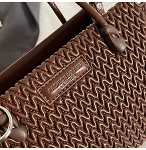 Detail of brown leather bucket bag with wavy quilted texture and silver metal ring