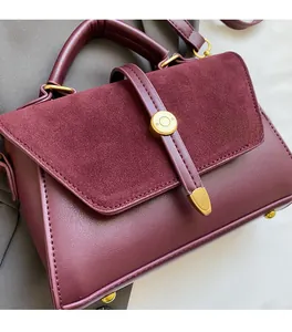 Detail of burgundy leather and suede crossbody bag with gold metallic circular buckle