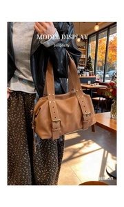 Detail view of a tan Boston tote bag featuring decorative straps and vintage metal buckles