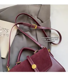 Detail of burgundy matte leather bag showing the adjustable strap and gold circular lock