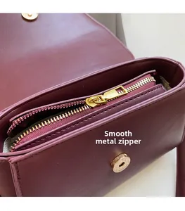 Close-up of premium gold hardware and smooth zipper on vintage burgundy leather handbag