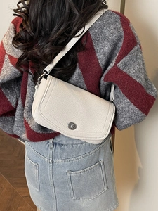 Sac à bandoulière minimaliste en cuir blanc cassé avec boucle argentée porté par un mannequin