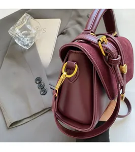Detail view of burgundy leather bag with matte texture and golden hardware accents