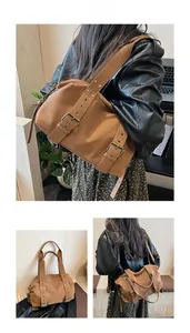 Detail of vintage brown tote bag with double buckle straps and bronze metal rivets