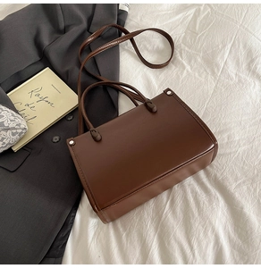 Flat lay of vintage dark brown faux leather bucket bag on white fabric background