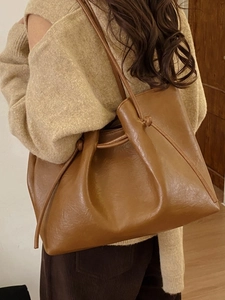 Brown large capacity vintage tote bag in soft leather worn by a model in a warm room