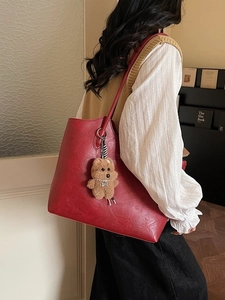 Vintage red leather tote bag for women with a brown plush bear charm for daily commute