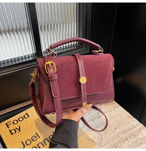 Close-up of burgundy matte suede texture and gold metal hardware on the shoulder bag