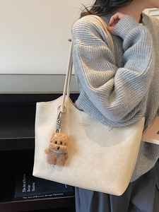 Minimalist beige oversized tote bag with textured faux leather and plush dog charm