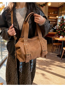 Detail of vintage brown leather tote bag with rivet accents and stylish buckle hardware