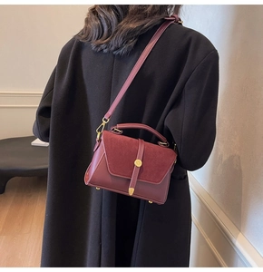 Rear view of a model wearing a reddish brown matte leather square crossbody handbag