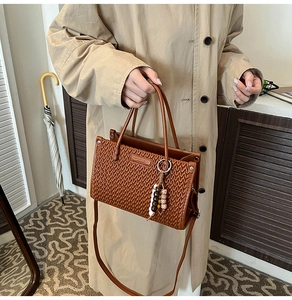Detail of brown bucket bag with wavy textured pattern and vintage bead charm