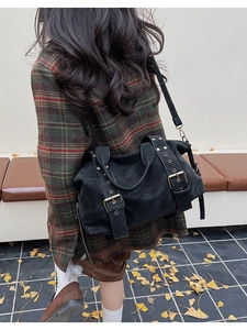 Retro black tote bag with vintage metal buckles worn by model in an outdoor setting