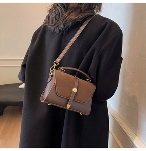 Close-up of brown leather and suede crossbody bag with gold hardware on model