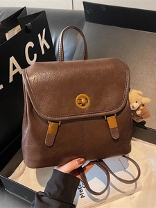 Vintage brown leather backpack with gold clasp and cute bear charm in a chic urban setting