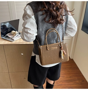Detailed shot of brown woven leather bucket bag with wooden bead charm and round handles