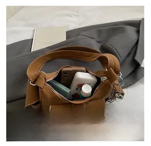 Interior storage view of brown shoulder bag with white stitching and metal heart charm
