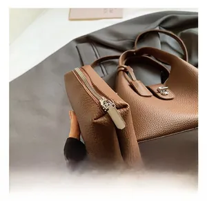 Detail of brown litchi pattern leather handbag and small zipper pouch with silver hardware