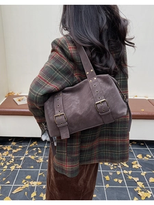 Detail of vintage tote bag with rivets and metal buckles on matte brown leather finish