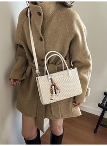 Close-up of beige woven bucket bag with vintage texture and ethnic beaded charm detail