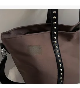 Macro shot of coffee brown tote bag featuring metallic stud detail and fabric texture