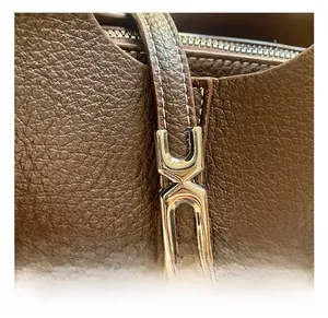 Macro detail of dark brown lychee grain leather with polished silver metal buckle