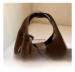 Detail of dark brown lychee grain leather bucket bag with silver metal lock closure