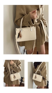 Detail view of cream woven bucket bag showing the beaded tassel and crossbody strap