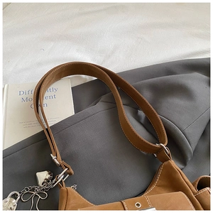 Detail of caramel leather shoulder bag with white contrast stitching and heart chain