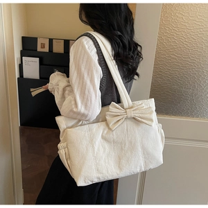 Gros plan sur un sac cabas blanc cassé avec grand nœud et poche latérale à cordon