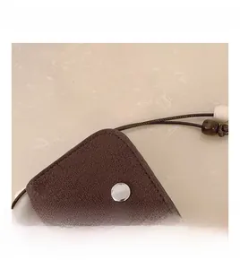 Close-up of retro brown suede mini bag with silver snap and beaded neck strap detail