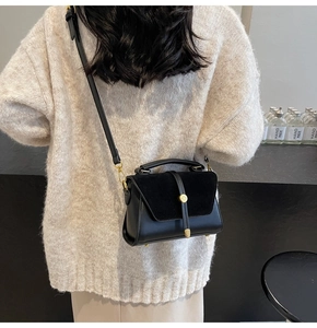 Close-up of matte black leather handbag with premium gold circular metal buckle