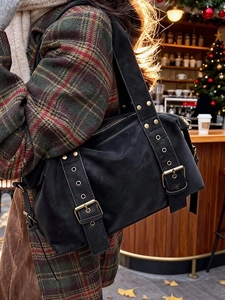 Chic black tote bag with gold rivets and vintage hardware worn by a model in winter
