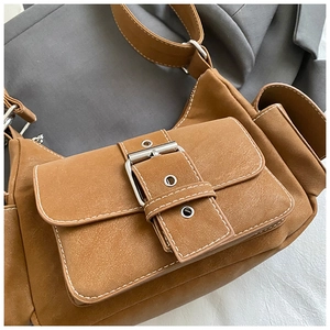 Detailed close-up of a retro brown shoulder bag with a metal buckle and white stitching