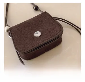 Detail of dark brown suede mini bag with silver buckle and decorative wooden bead
